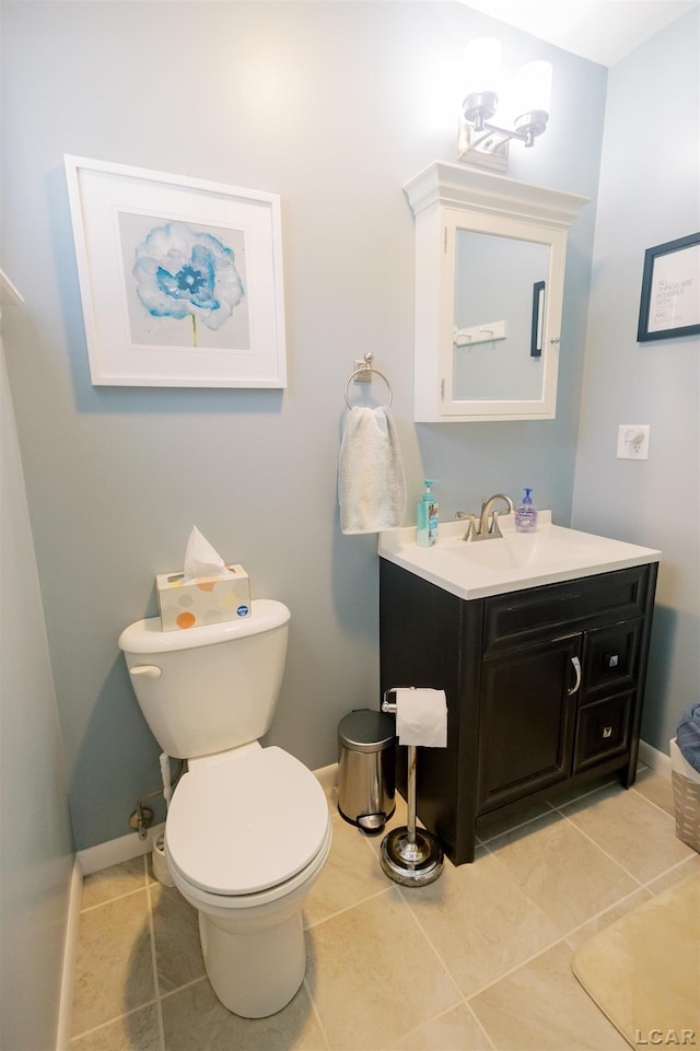 half bath with tile patterned floors, toilet, vanity, and baseboards