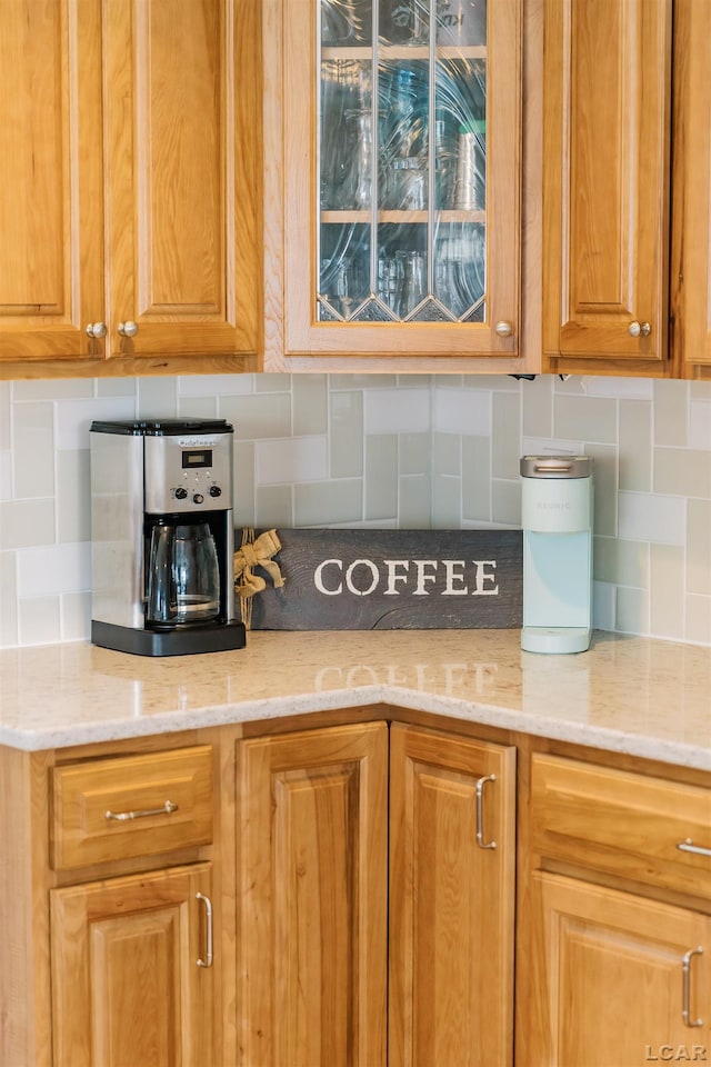 kitchen with light stone countertops, backsplash, and brown cabinets