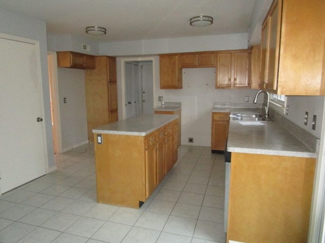 kitchen with brown cabinetry, light tile patterned flooring, light countertops, and a sink