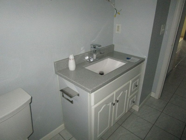 half bathroom featuring tile patterned floors, toilet, vanity, and baseboards