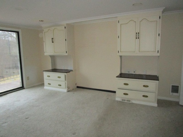 empty room featuring visible vents, baseboards, light colored carpet, and ornamental molding