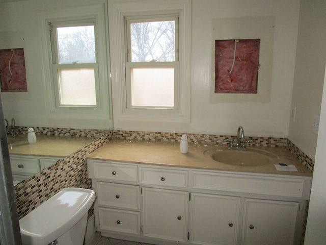 bathroom with vanity, toilet, tasteful backsplash, and a wealth of natural light