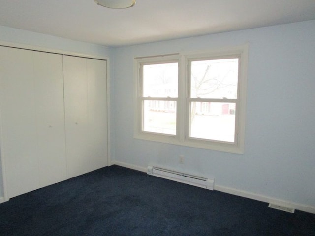 unfurnished bedroom with a closet, baseboards, baseboard heating, and dark carpet