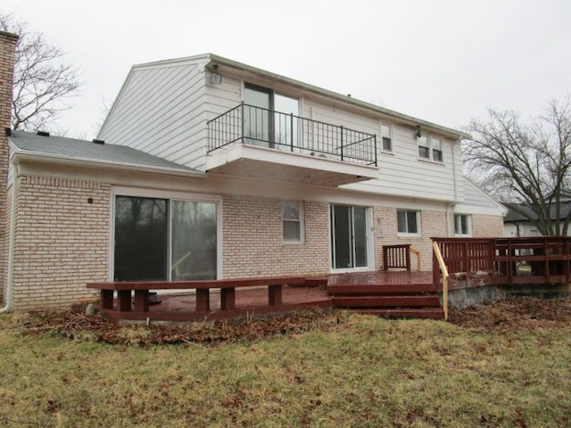 back of house featuring brick siding, a yard, and a balcony