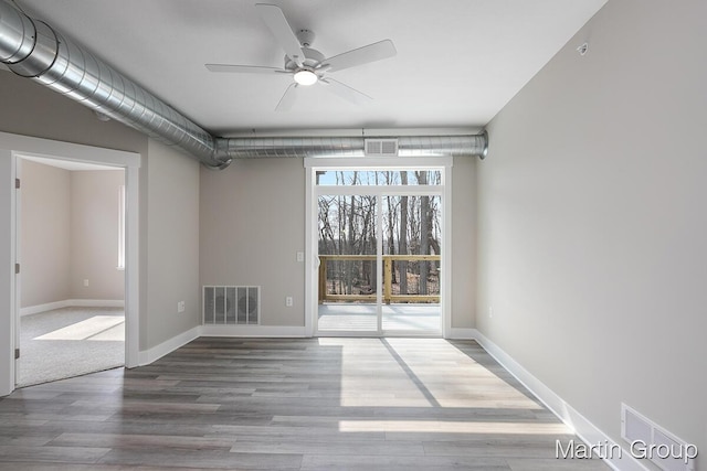 spare room with wood finished floors, visible vents, and baseboards