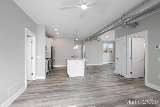 kitchen with visible vents, light wood finished floors, white cabinets, appliances with stainless steel finishes, and open floor plan