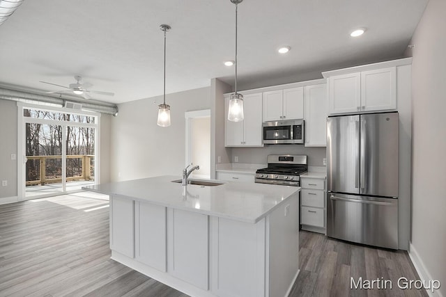 kitchen with a sink, appliances with stainless steel finishes, wood finished floors, and white cabinets