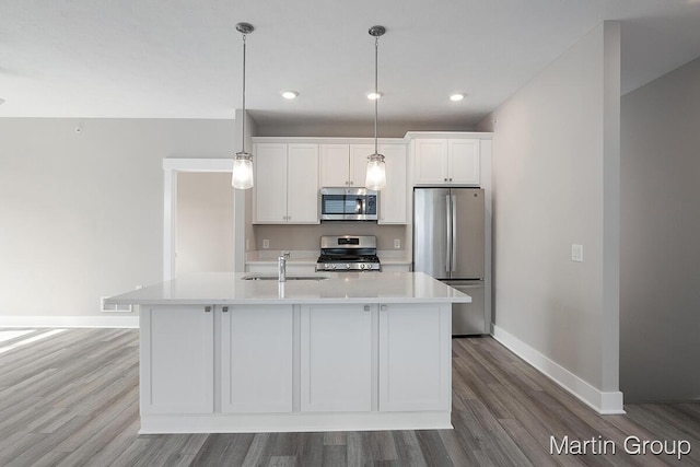 kitchen with baseboards, light countertops, appliances with stainless steel finishes, white cabinets, and a sink