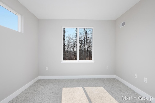 spare room with visible vents, carpet flooring, a healthy amount of sunlight, and baseboards