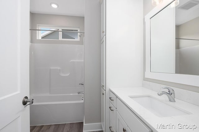 full bath with vanity, wood finished floors, washtub / shower combination, and visible vents