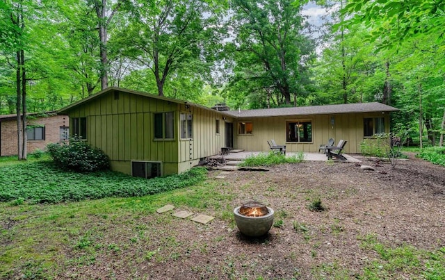 rear view of house featuring a fire pit, board and batten siding, and a patio area