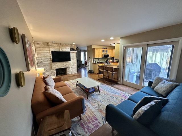 living room with recessed lighting, a stone fireplace, and light wood finished floors