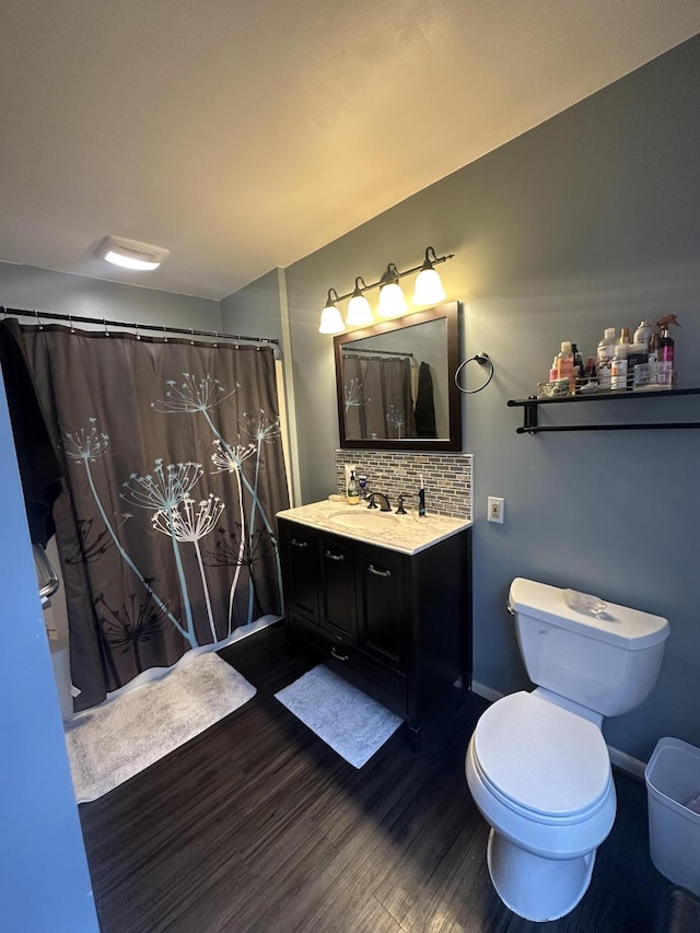 bathroom featuring toilet, tasteful backsplash, wood finished floors, baseboards, and vanity