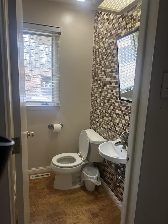 bathroom with a sink, visible vents, baseboards, and toilet