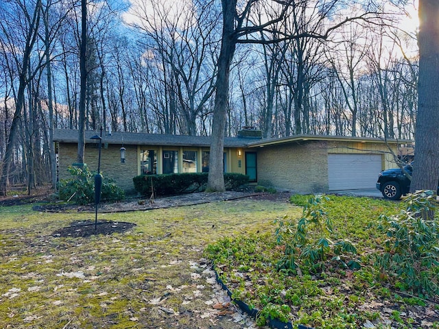 view of front of home with a garage, a chimney, and a front lawn