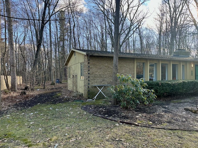 view of side of home featuring board and batten siding, a lawn, stone siding, and a chimney