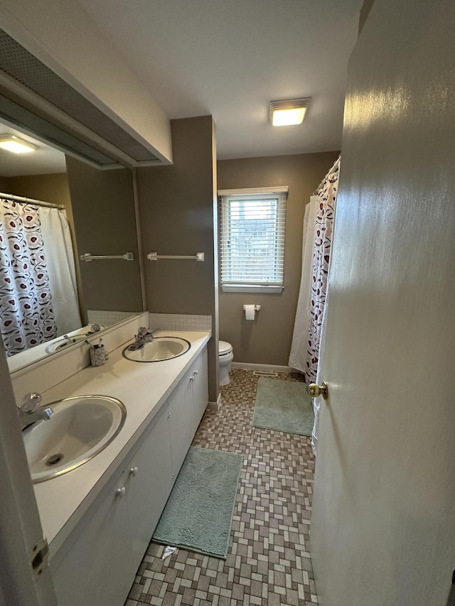 full bathroom featuring double vanity, tile patterned floors, toilet, and a sink