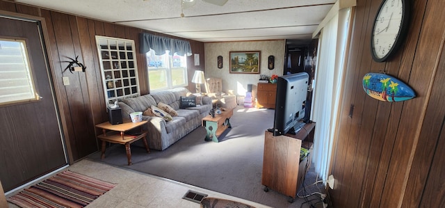 living room featuring tile patterned floors, visible vents, and wood walls