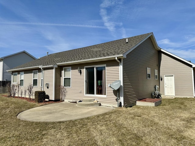 rear view of house with entry steps, a patio area, a lawn, and a shingled roof