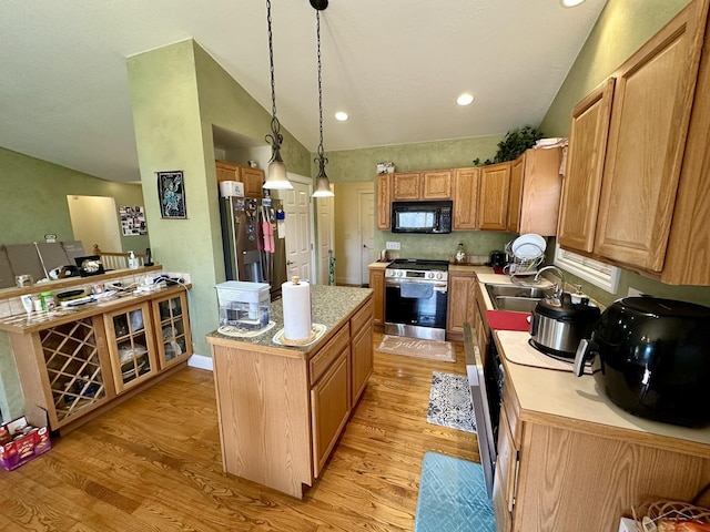 kitchen with lofted ceiling, a sink, stainless steel appliances, light countertops, and light wood-style floors