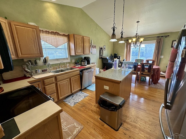 kitchen featuring lofted ceiling, light wood-style flooring, a sink, appliances with stainless steel finishes, and a chandelier