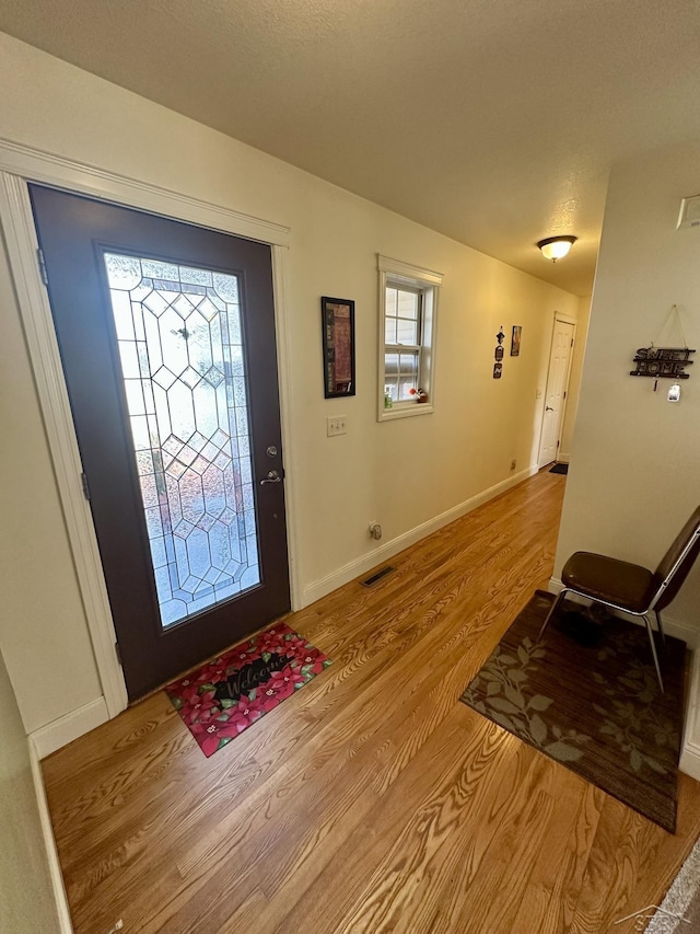 foyer featuring baseboards, visible vents, and light wood finished floors