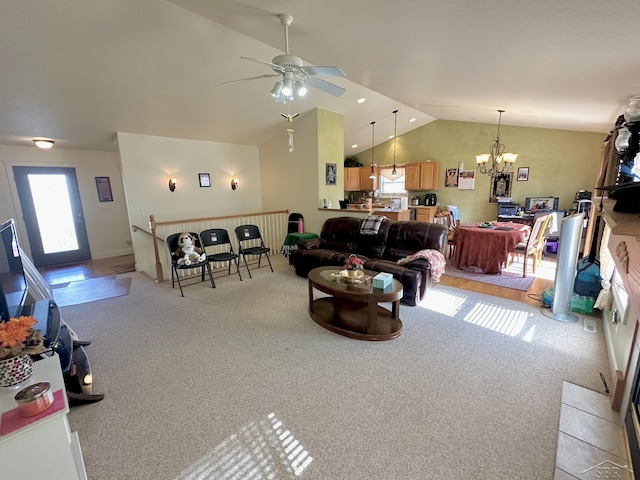 living area featuring high vaulted ceiling, ceiling fan with notable chandelier, and light carpet