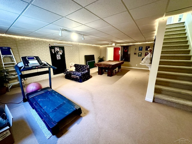 exercise area featuring pool table, brick wall, a paneled ceiling, and carpet