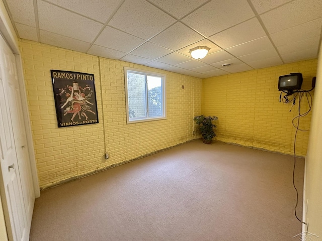 basement with a drop ceiling and brick wall