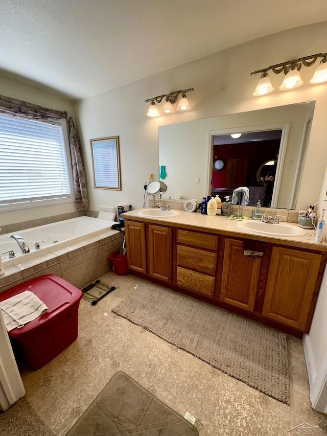 full bath featuring double vanity, a tub with jets, and a sink