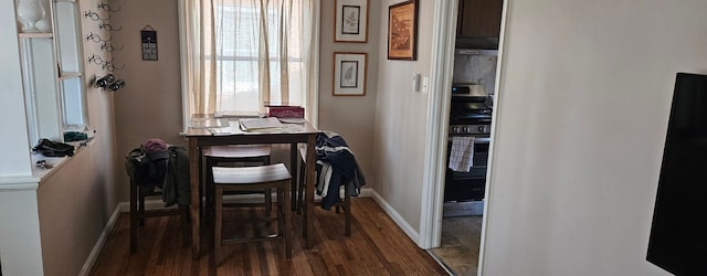 dining space featuring dark wood-type flooring and baseboards