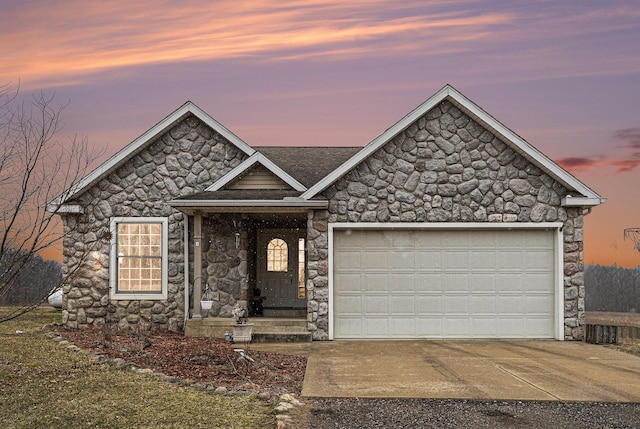 view of front of house featuring stone siding, a garage, and driveway