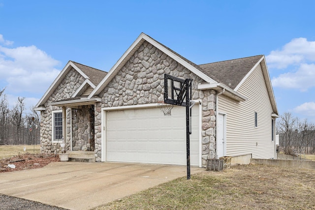 view of front of property featuring stone siding, an attached garage, driveway, and roof with shingles