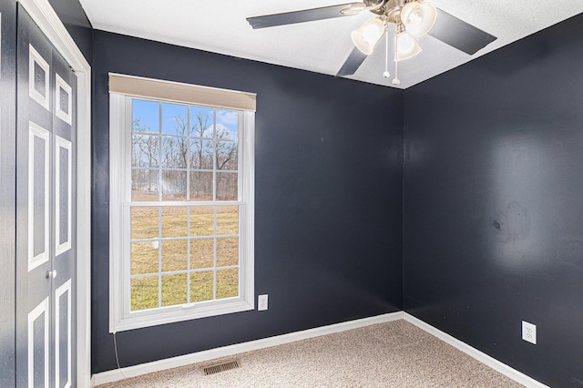 empty room with a ceiling fan, baseboards, visible vents, and carpet floors