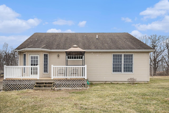 rear view of house featuring a deck, a gazebo, a yard, and roof with shingles