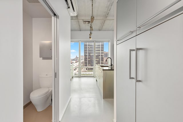 hallway featuring a sink, a city view, baseboards, and concrete floors