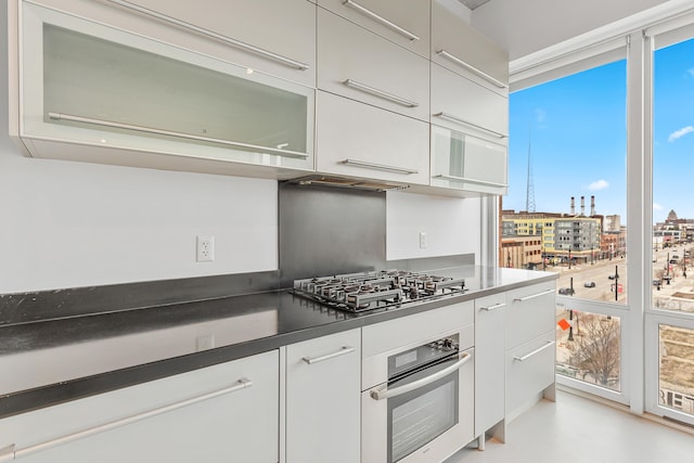 kitchen with a view of city, modern cabinets, dark countertops, stainless steel appliances, and white cabinets