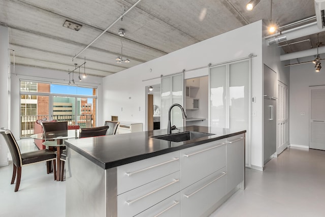 kitchen featuring a sink, a barn door, dark countertops, and modern cabinets