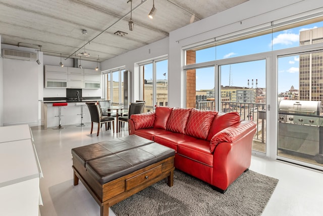 living area with a view of city, concrete floors, and a wall mounted AC