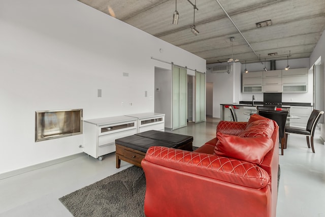 living area featuring ceiling fan, concrete flooring, and a barn door