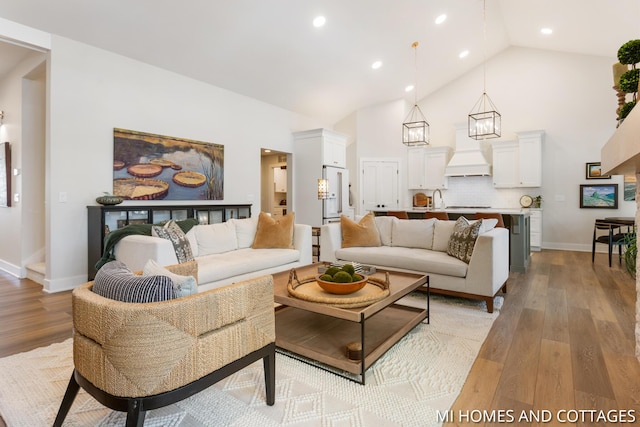 living area with recessed lighting, light wood-style flooring, high vaulted ceiling, and baseboards