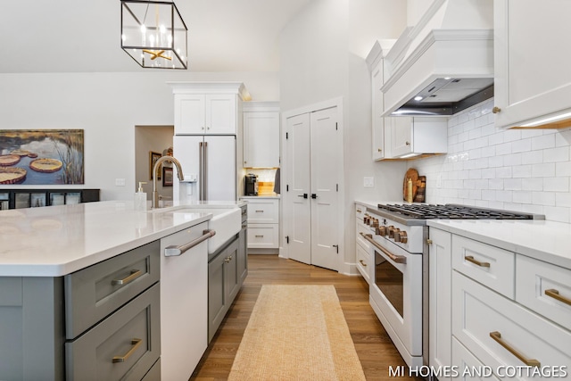 kitchen with gray cabinets, white appliances, light countertops, and custom range hood