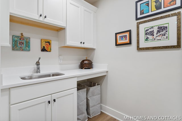 laundry room featuring wood finished floors, baseboards, and a sink