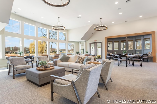 living area featuring visible vents, light colored carpet, recessed lighting, a high ceiling, and an inviting chandelier