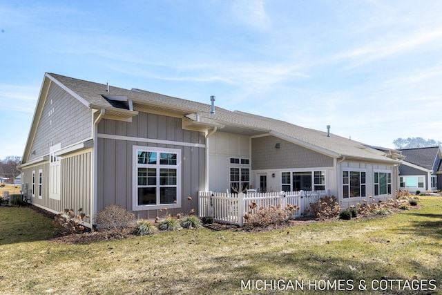 rear view of property featuring a lawn, board and batten siding, and fence