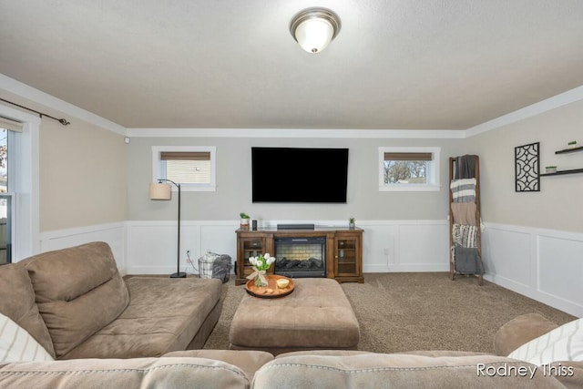 carpeted living room featuring plenty of natural light, a glass covered fireplace, and wainscoting