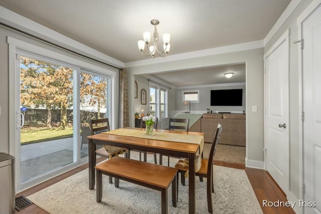 dining room featuring a notable chandelier, baseboards, dark wood-type flooring, and ornamental molding