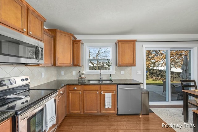 kitchen featuring a sink, light wood-style floors, brown cabinets, and stainless steel appliances