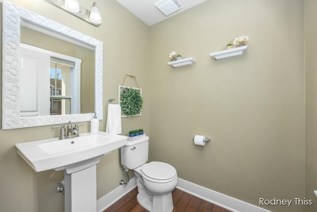 half bathroom with visible vents, baseboards, toilet, and wood finished floors