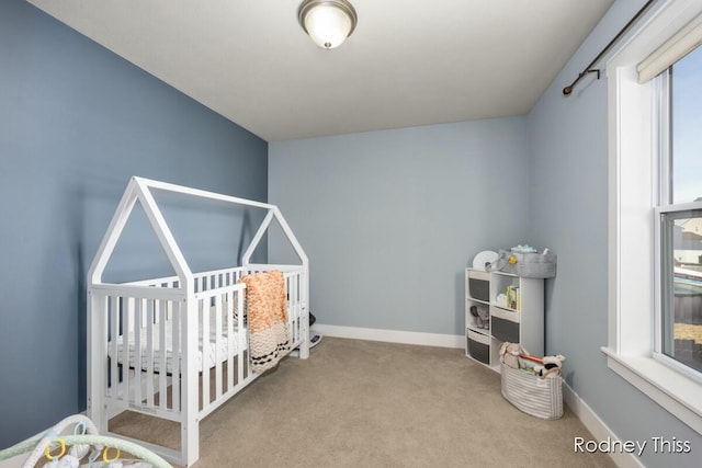 bedroom featuring a crib, carpet, and baseboards